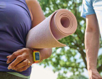 close-up of senior woman holding a yoga mat outside