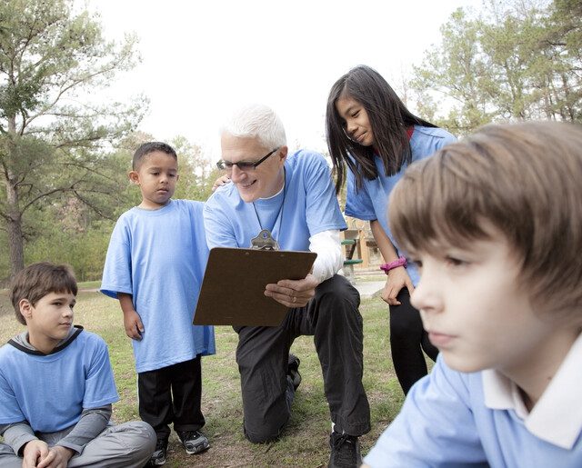 Senior man volunteer coaches group of neighborhood children.