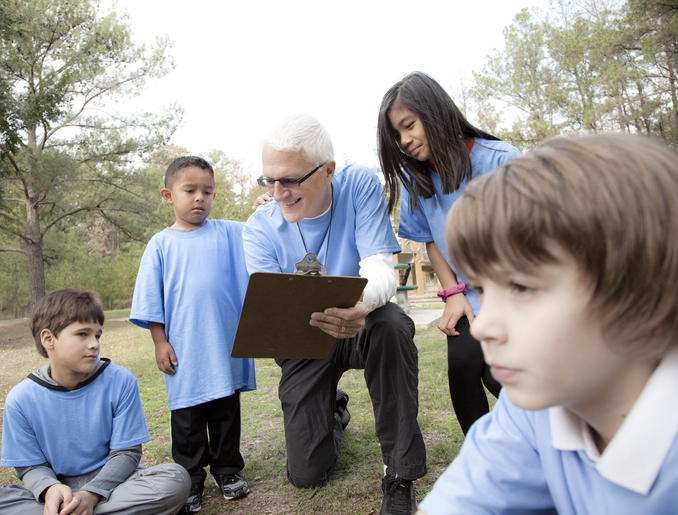 Senior man volunteer coaches group of neighborhood children.